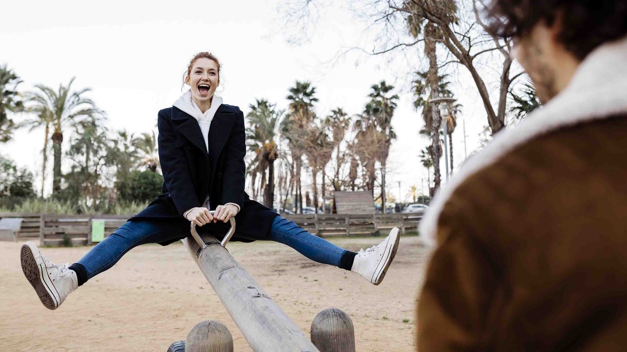 A jubilant woman rides a seesaw