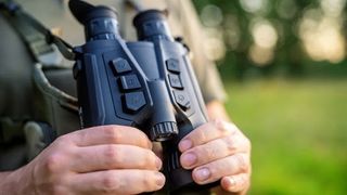 Hikmicro Habrok Pro binoculars being held by a man outdoors