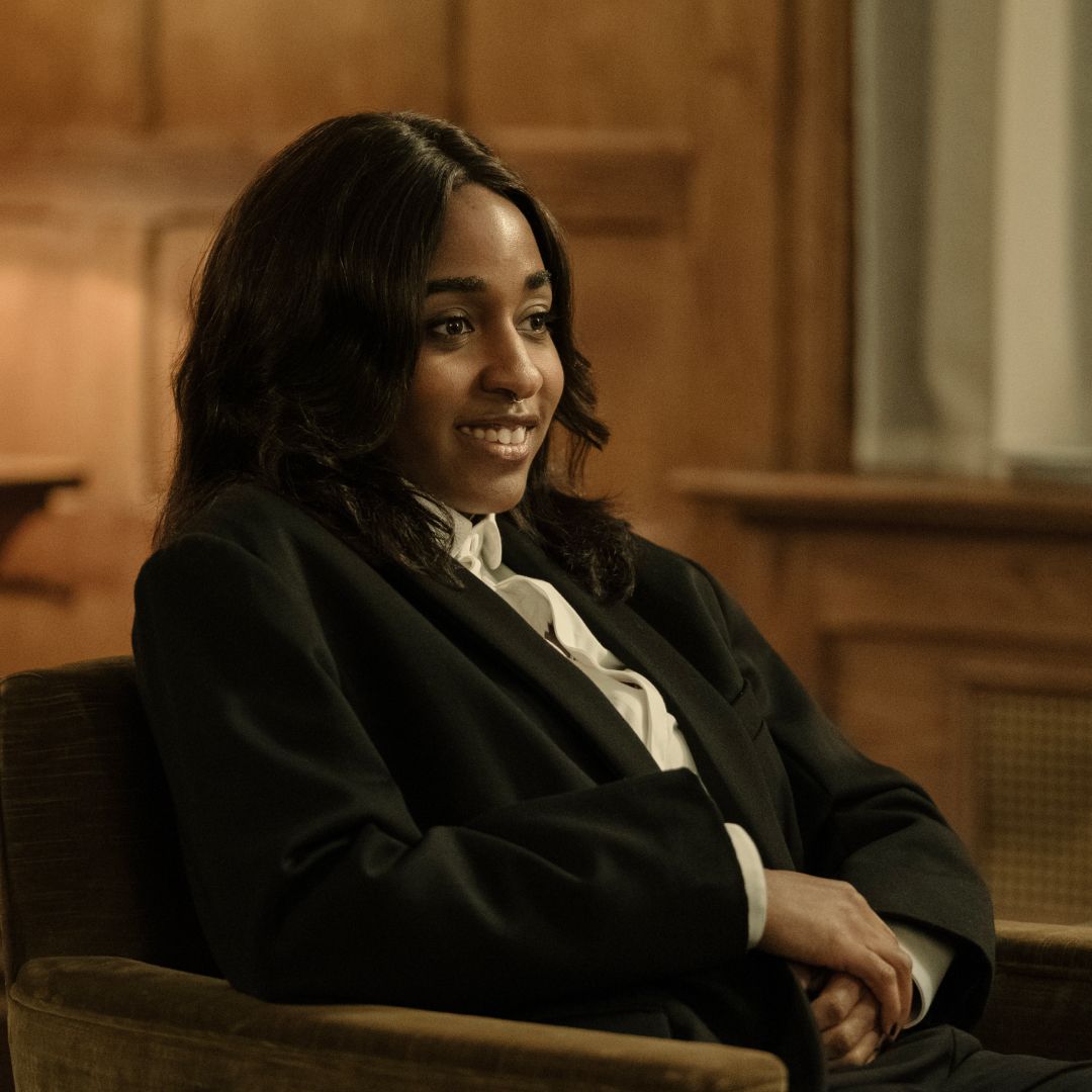 ayo edebiri as maggie wearing a blazer sitting in a chair at a party in after the hunt