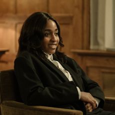 ayo edebiri as maggie wearing a blazer sitting in a chair at a party in after the hunt