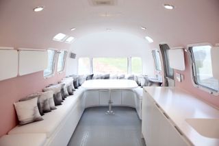 Interior of a bus with pastel decor, white sofa and canvas throw cushions