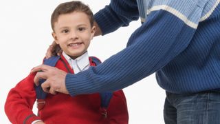 Parent helping son get ready for school