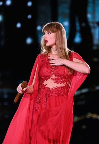 Taylor Swift wears a red alberta ferretti dress on the eras tour with stomach cut outs and a semi sheer cape