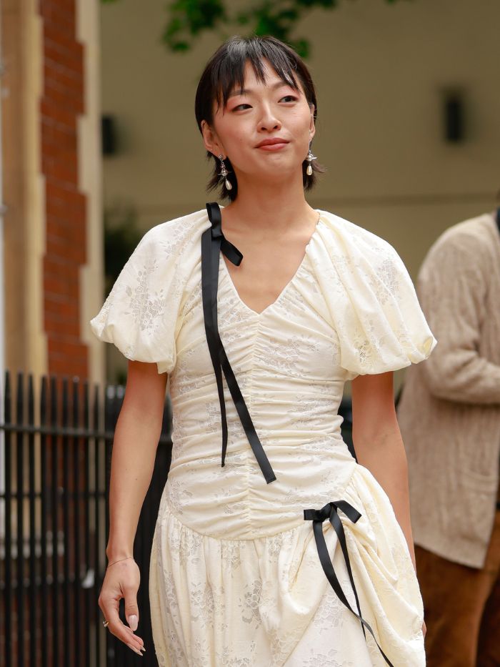 A woman at London Fashion Week wearing a cream dress with a short haircut and a wispy fringe