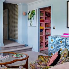 A sky blue-painted living room with a set of floral-print chairs and a glass coffee table