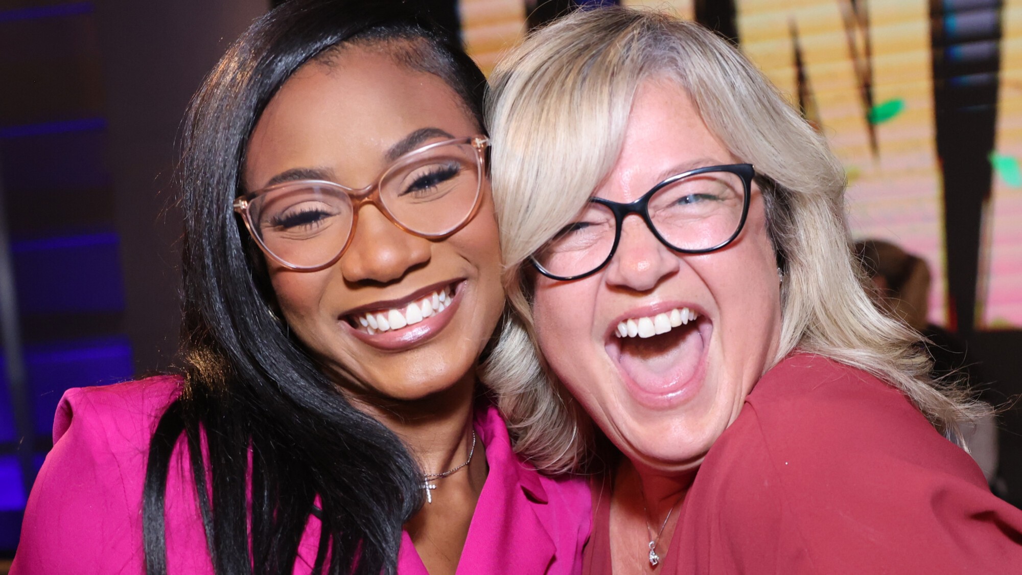 Taylor and Angela posing together and smiling on the Big Brother stage during the Season 28 finale. Taylor is wearing a pink shirt. Angela was wearing red. 