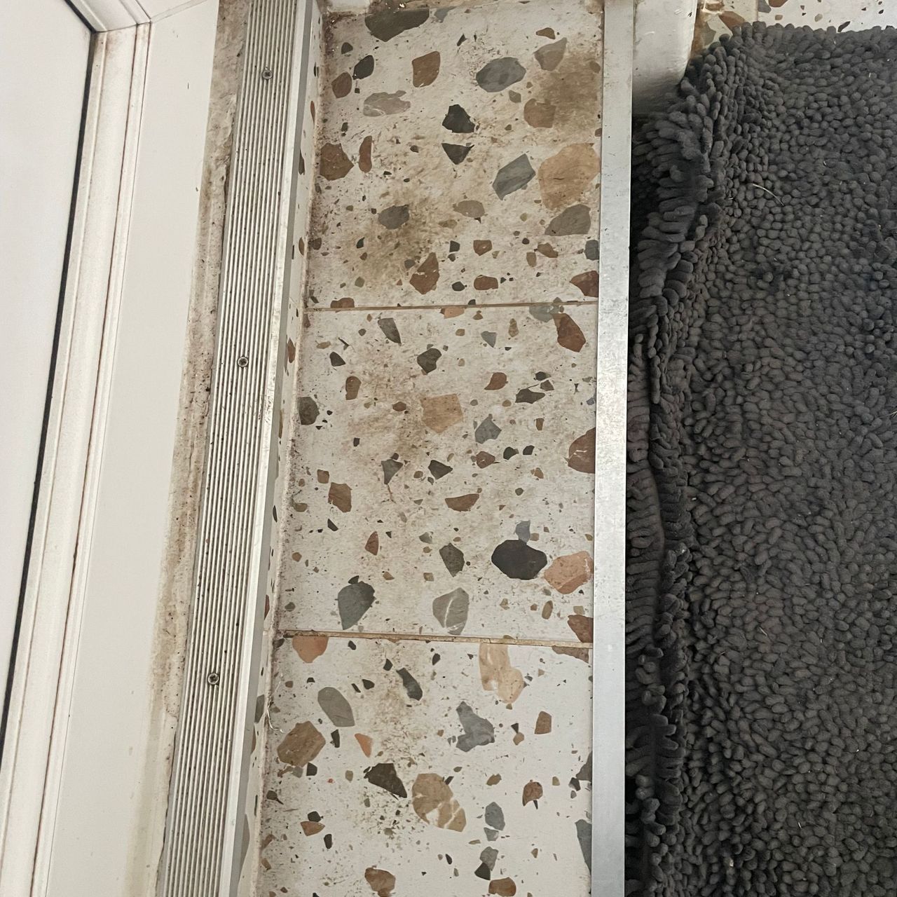 Terrazzo tiled kitchen step with a grey mat next to it