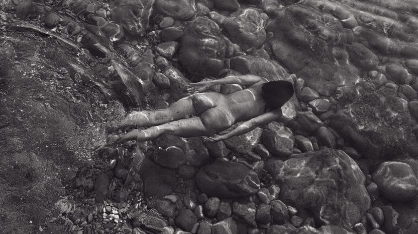 Black &amp; white image of a naked woman floating face down in water