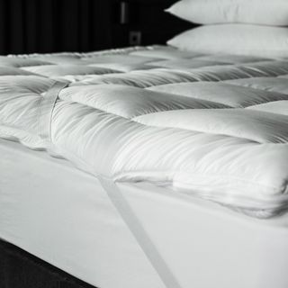 Thick white mattress topper on bed