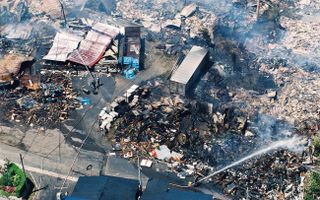 In this aerial image, self-defense force members extinguish fire in debris after the tsunami triggered by the magnitude-7.8 earthquake hit Okushiri Island on July 13, 1993.