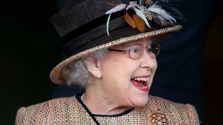The Queen pranked - Queen Elizabeth II (wearing her gold and ruby floral trellis brooch) watches her horse 'Sign Manual' run in and win the Dreweatts Handicap Stakes as she attends the Dubai Duty Free Raceday at Newbury Racecourse on April 19, 2013 in Newbury, England.
