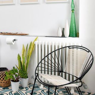 floor house plants in white bathroom next to wire chair