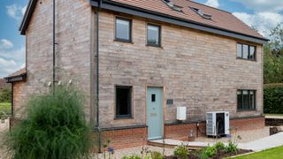 Timber clad new self build with green front door and air source heat pump