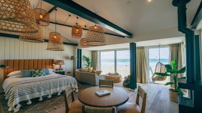 Image of inside a bedroom at Watergate Bay. The bed to the left is made and the natural light shines through the door windows to the blue sky 