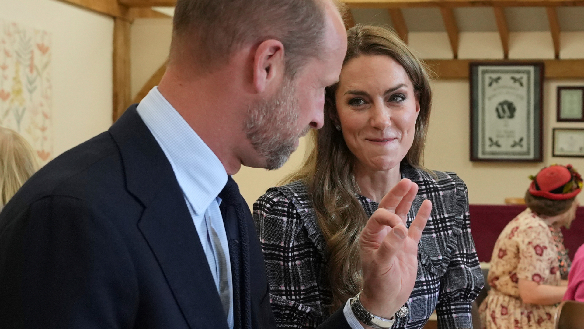 Kate Middleton wears a plaid dress and tries to contain her laughter while Prince William says something funny