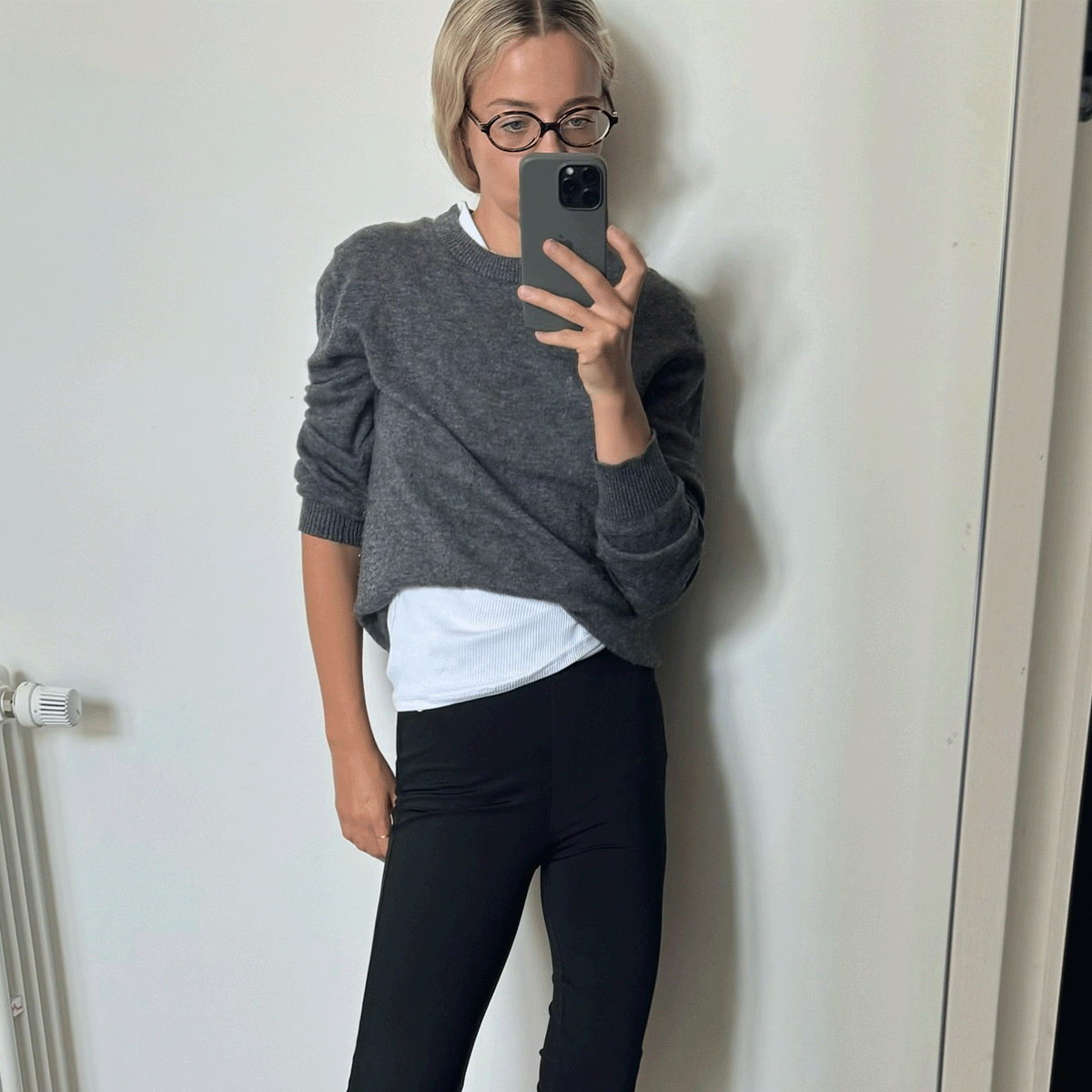 Stephanie Broek wearing a grey sweater and white t-shirt with glasses.