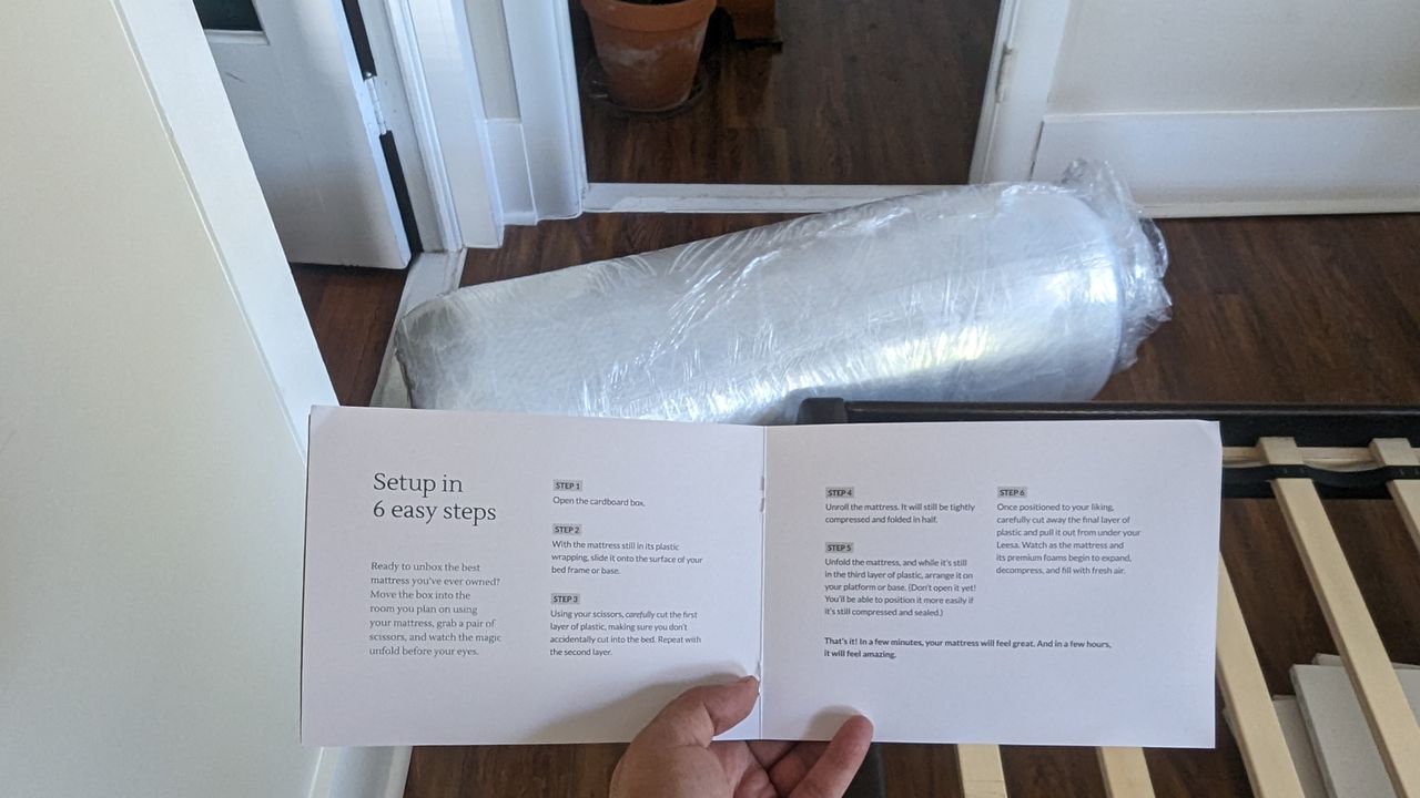 Leesa Oasis Chill Hybrid review image shows the mattress unboxed but still in its shrinwrap, with our lead tester holding out the set up instructions