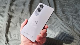 OnePlus Nord CE 4 Lite holdes op over et lysegrønt gardin.