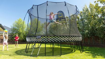 girl bouncing on a trampoline in a large garden in summer