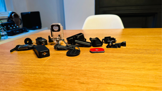 The SJCAM C300 accessories including a waterproof case sitting on a wooden table