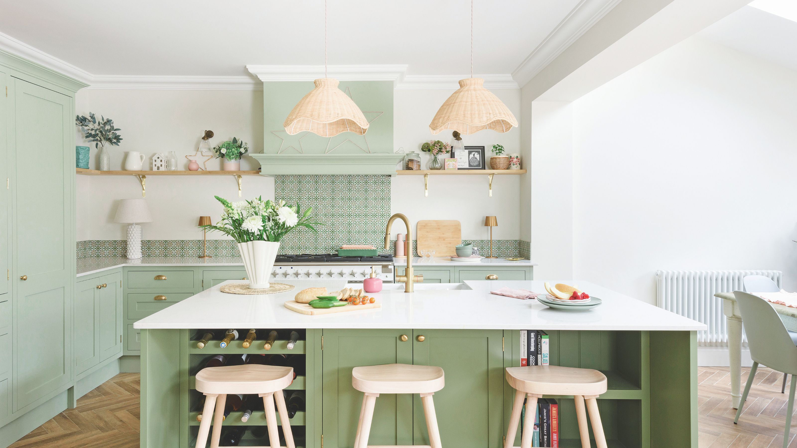 Open plan kitchen diner with green kitchen cabinets and white worktops and walls
