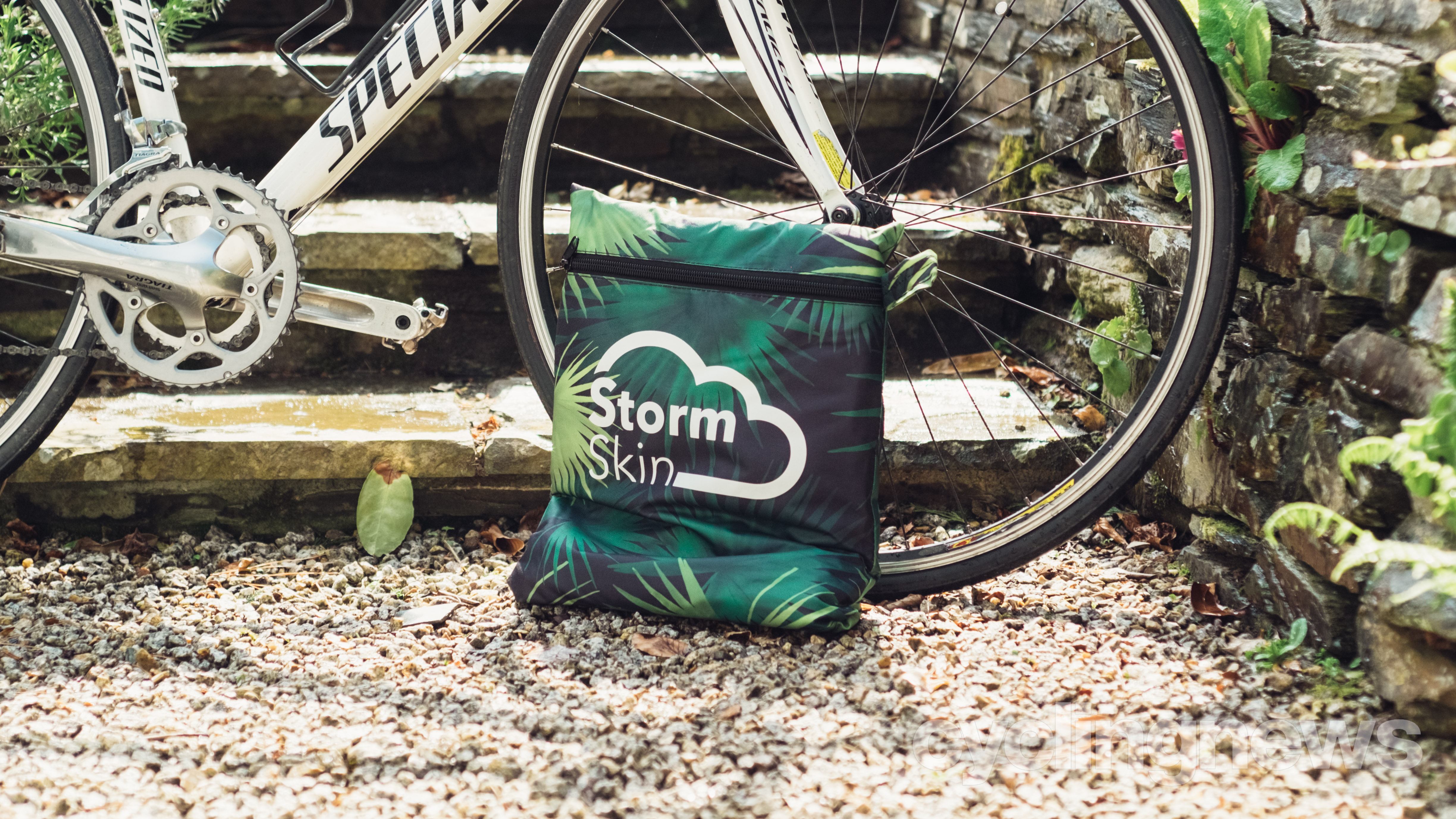 A bike cover in a square bag next to a bike wheel