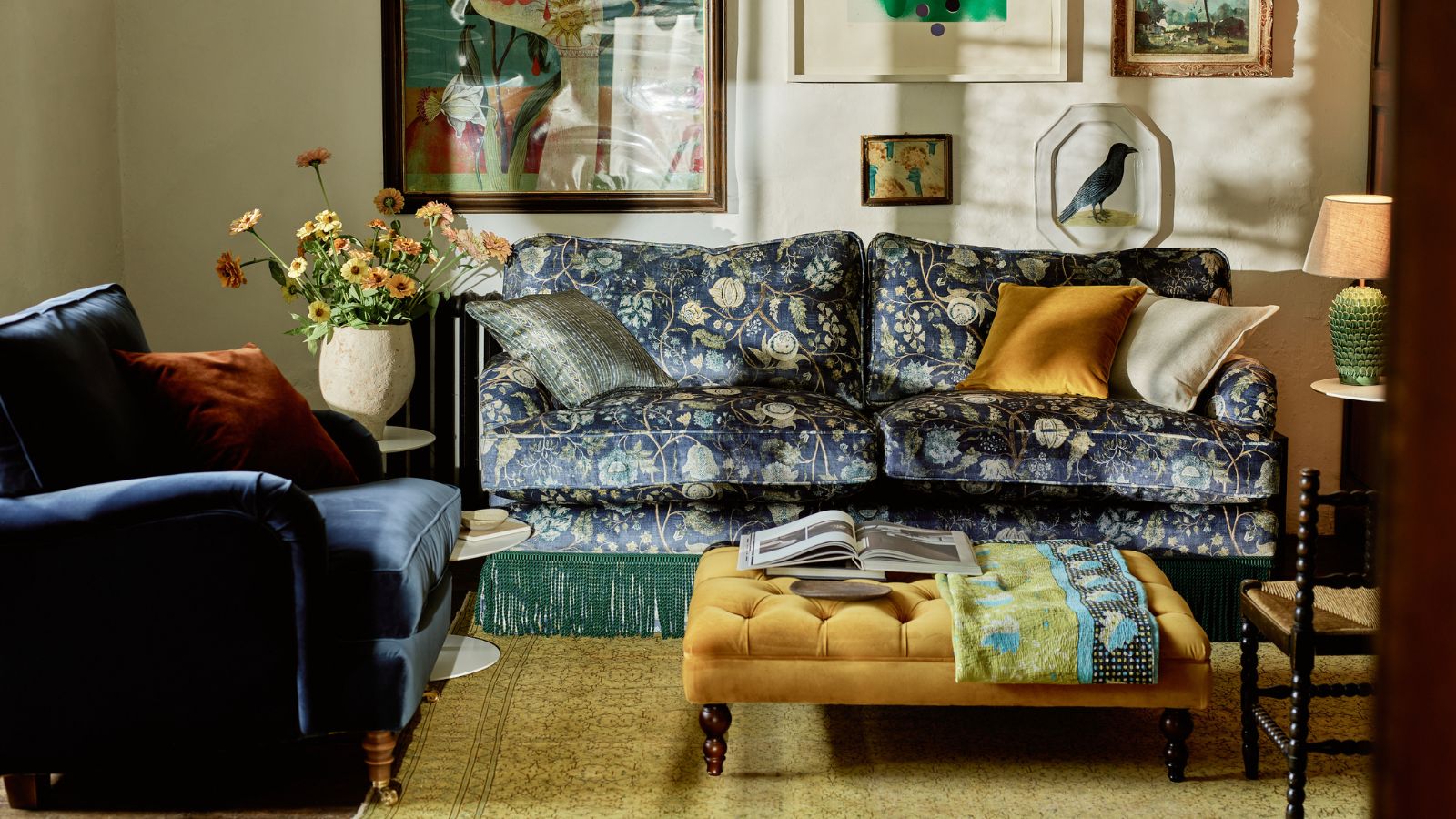 Velvet blue sofas in cozy living room with yellow ottoman and and wall art 
