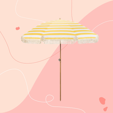 Livarno Home parasol in butter yellow on a pink background.
