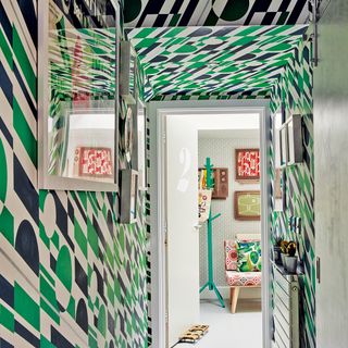 brightly patterned wallpaper with green and black shapes that covers the walls and ceiling in a hallway