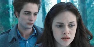 Edward Cullen stands behind Bella Swan in the woods in Twilight
