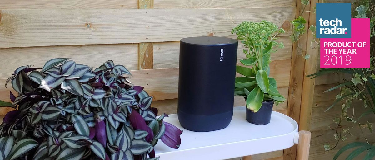 The Sonos Move wireless speaker in black pictured on a white table in a garden