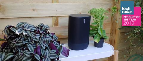 The Sonos Move wireless speaker in black pictured on a white table in a garden