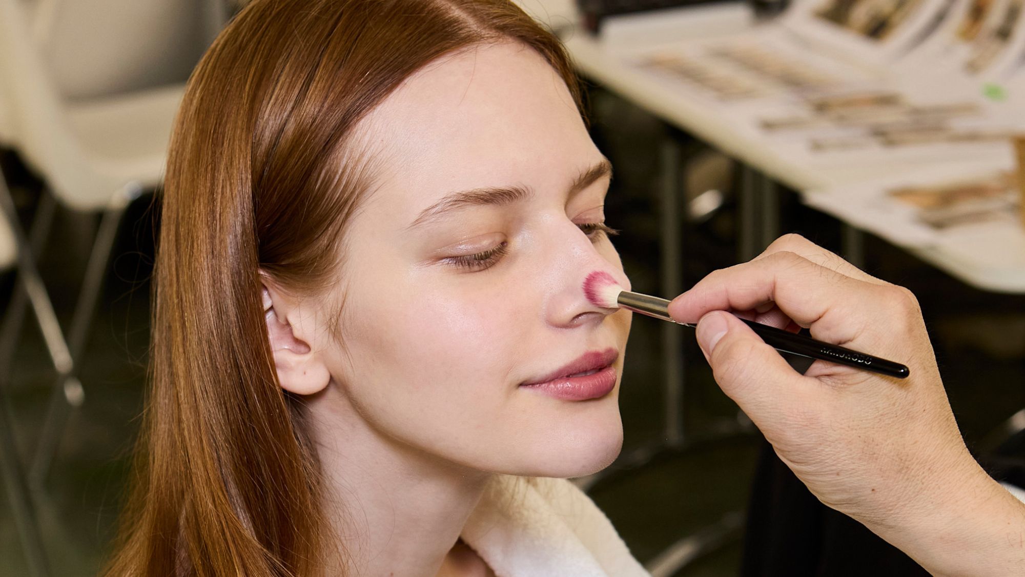 model backstage at fashion week having foundation applied