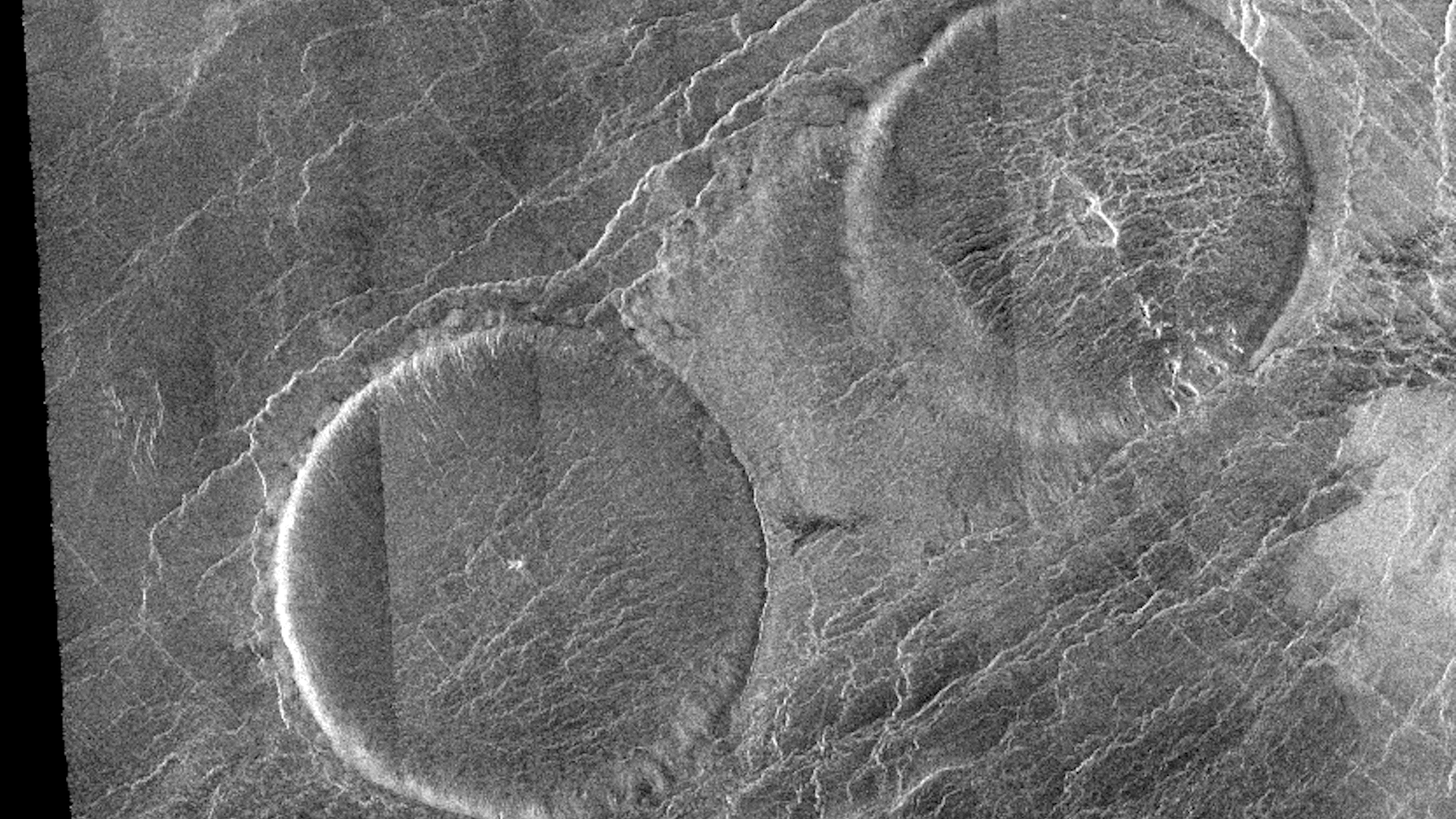 a black and white aerial image of circular shapes on Venus' surface