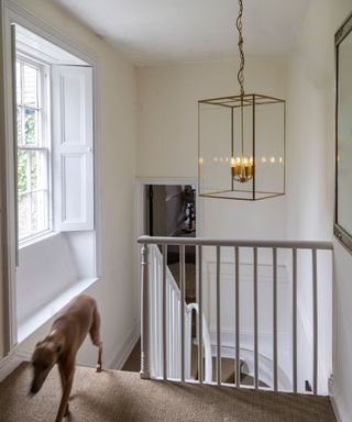 landing with white handrail and large rectangular brass pendant light