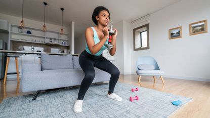 A woman performing a goblet squat with a dumbbell as part of a leg workout