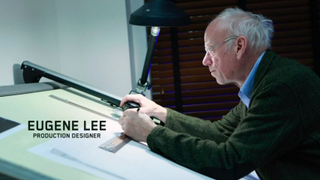 Eugene Lee working at a desk and looking at plans on SNL in a title card.