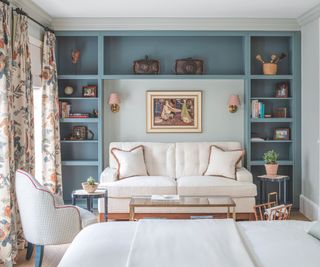 seating area in bedroom with sofa and armchair and inbuilt bookshelf in blue