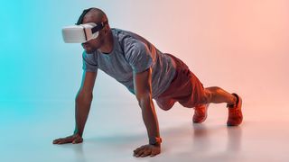 Young African man in sports clothing doing plank while wearing VR headset