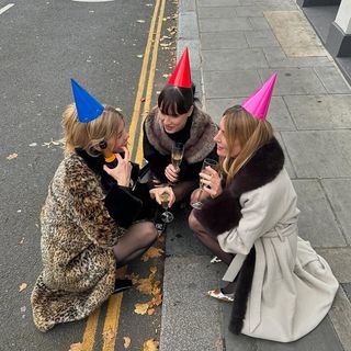 Three Women Wearing Coats and Party Hats