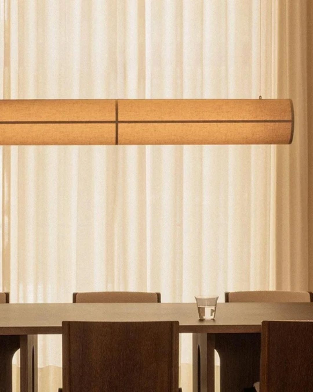 Audo Copenhagen Hashira Linear Pendant Lamp installed in warmly lit dining room above a table.