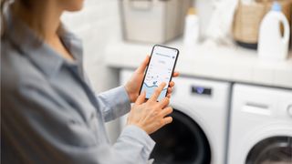 Woman using phone in front of washer