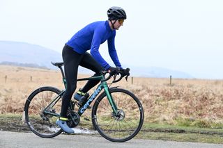 cyclist standing up riding a green bike wearing a blue jersey