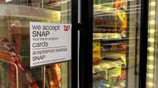 Bilingual sign on door of frozen food aisle, "We accept SNAP food stamp cards", at a Walgreens in Queens