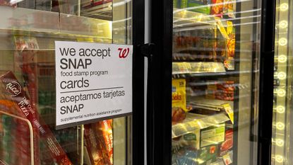 Bilingual sign on door of frozen food aisle, "We accept SNAP food stamp cards", at a Walgreens in Queens