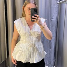 Woman wears white top and black trousers