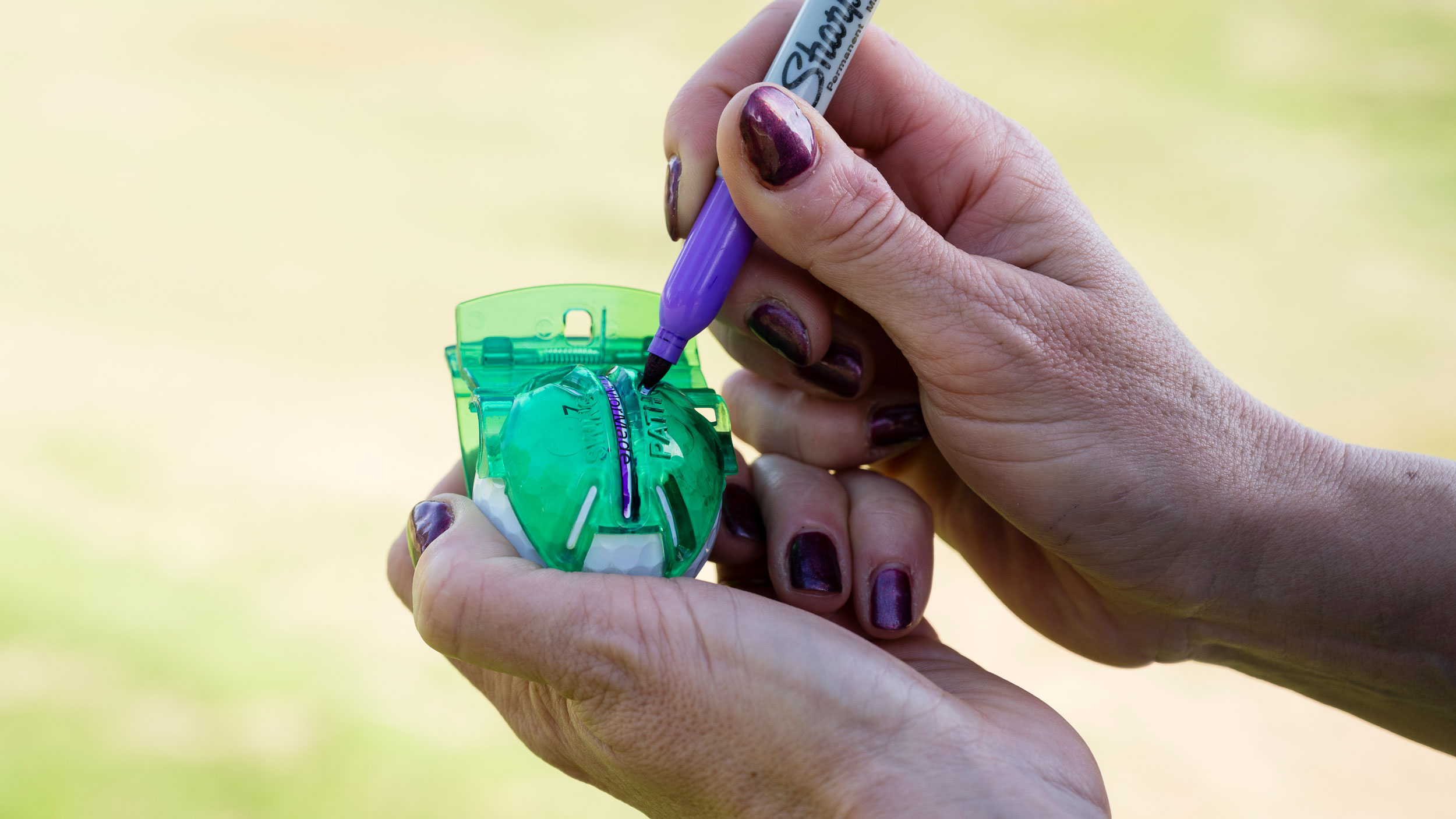 Sharpie and stencil being used to draw a line on a golf ball