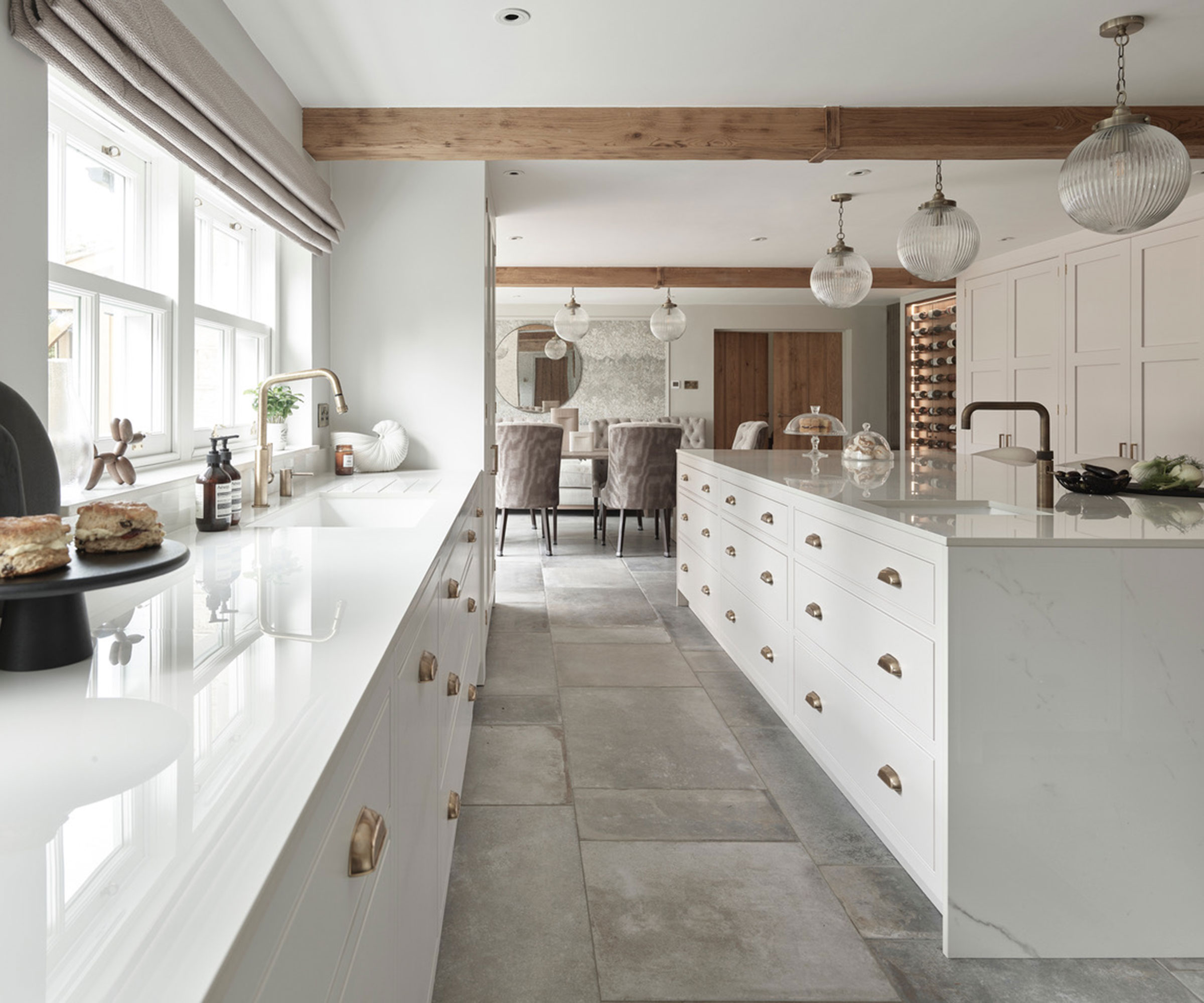 classic white streamlined kitchen with light slate flooring and brass cabinet hardware