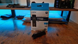 Crucial T700 Pro review image of the SSD next to its packaging on a gaming desk