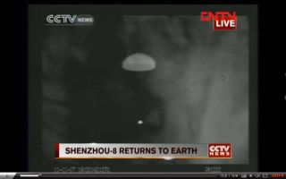 This screenshot of a CNTV Chinese news broadcast shows an infrared view of the unmanned Shenzhou 8 spacecraft as it descends to Earth under its parachute on Nov. 17, 2011. The spacecraft landed in inner Mongolia to end China's first space docking mission.